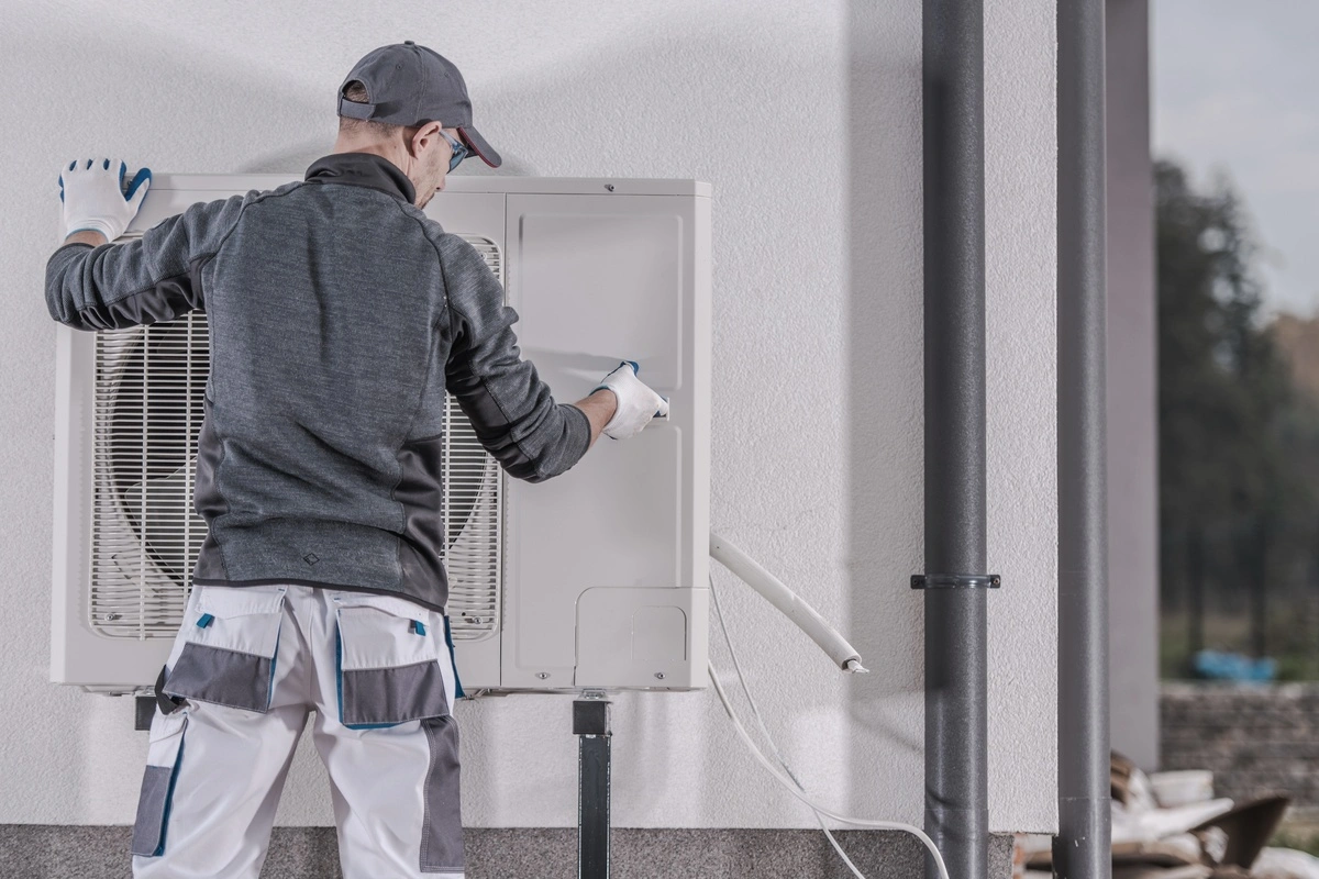 professionnel installant une pompe à chaleur contre un mur extérieur